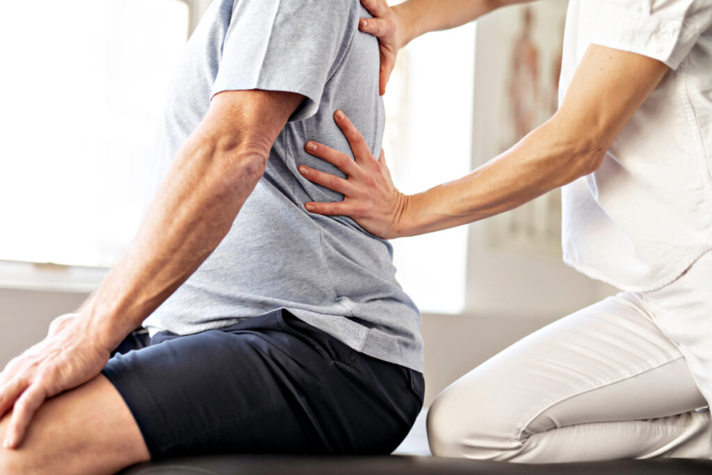 Physical Therapist Accesses Patient Back Pain