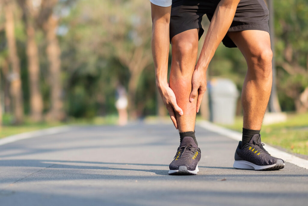 Young fitness man holding sprained leg